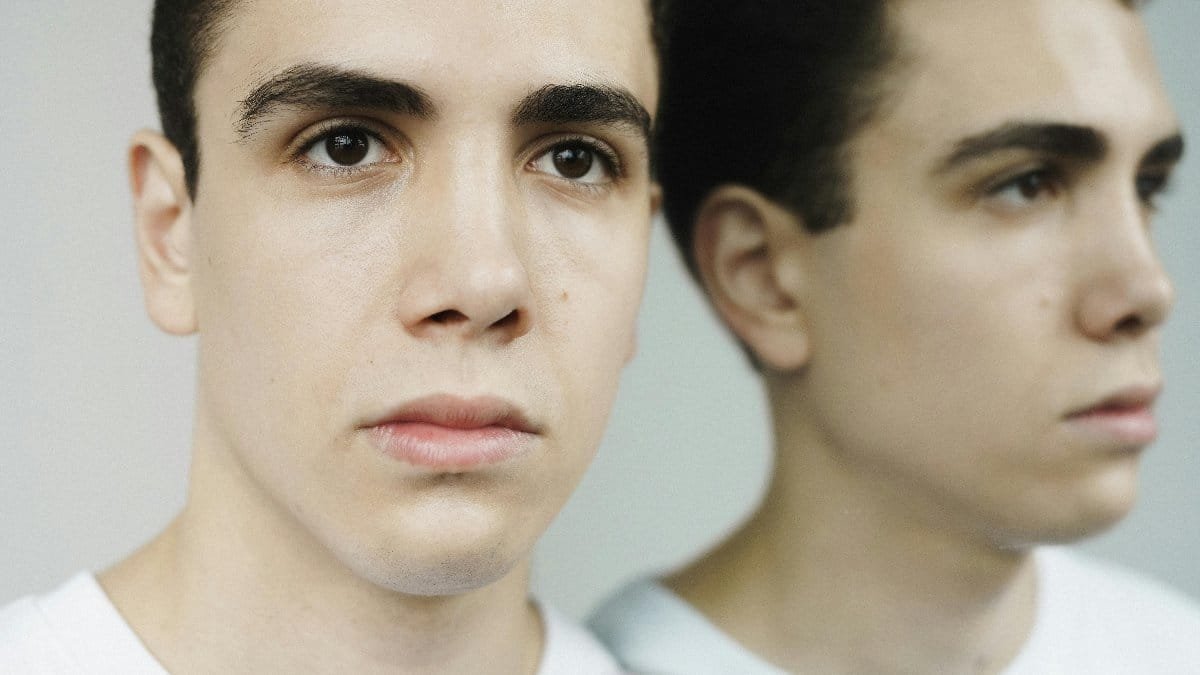 Close-up portrait of a young man gazing into a mirror, showcasing reflection. via Pexels