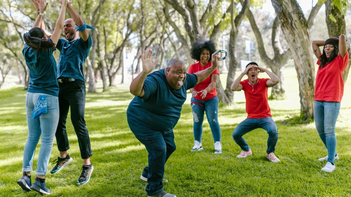 Diverse group enjoying team building games outdoors with joyful expressions. via Pexels