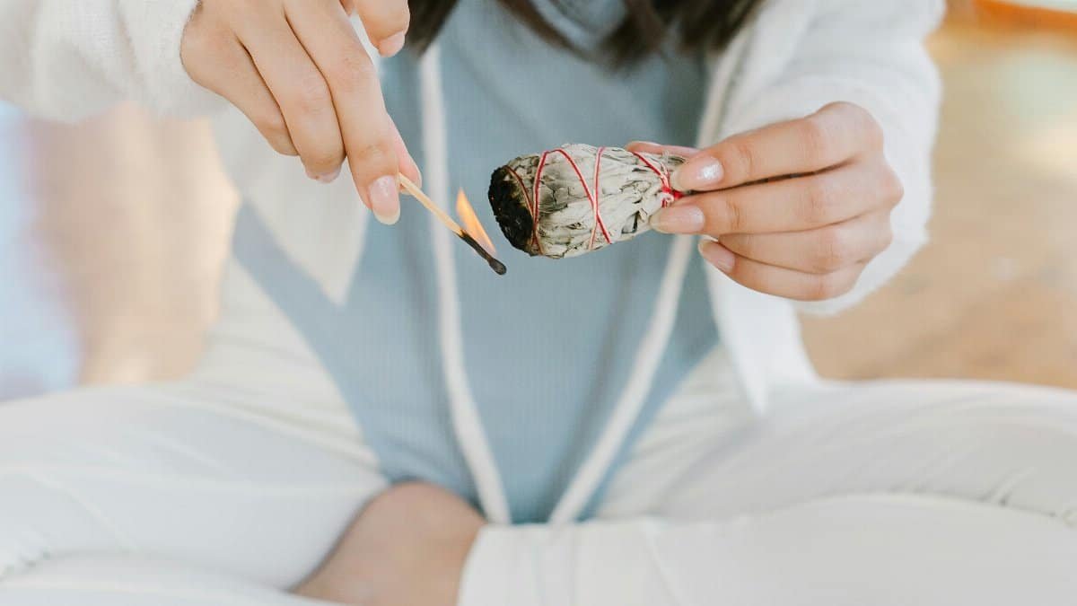 A serene scene of a woman meditating with burning sage and tarot cards. via Pexels