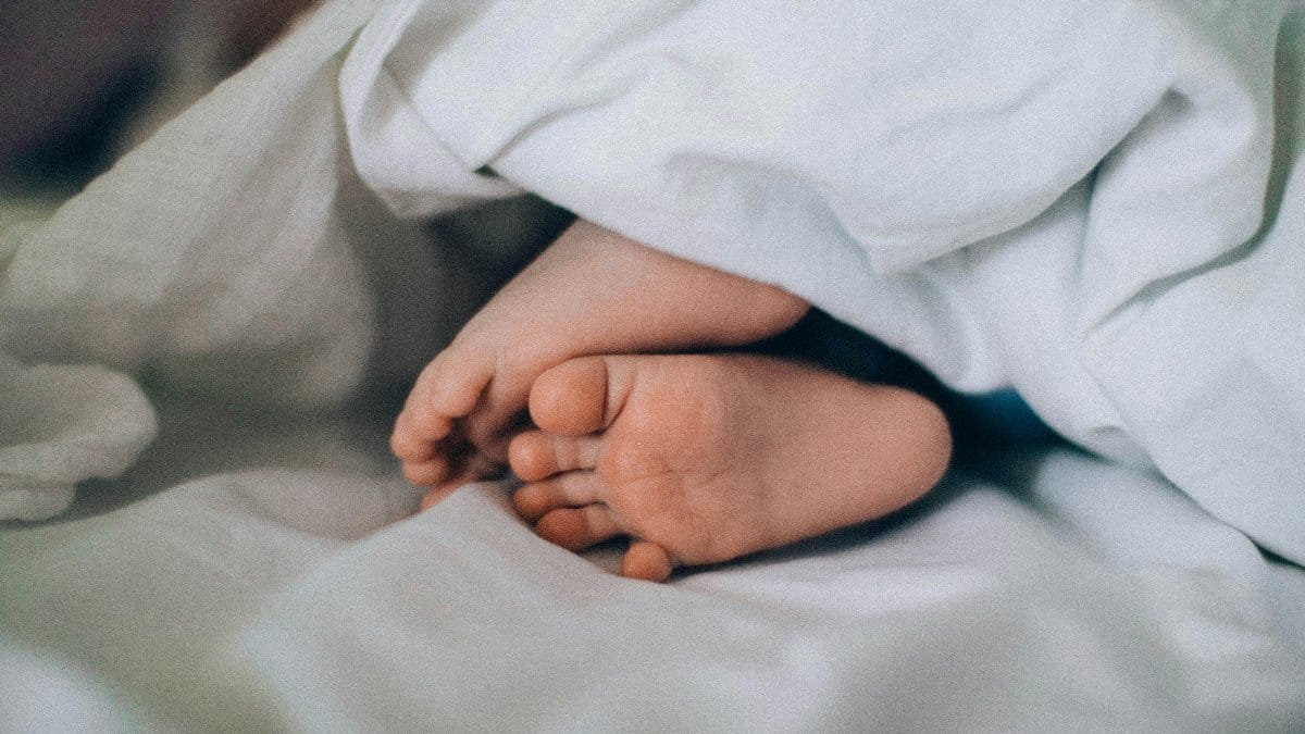 Close-up of tiny baby feet under a blanket, creating a cozy, cute vibe. via Pexels