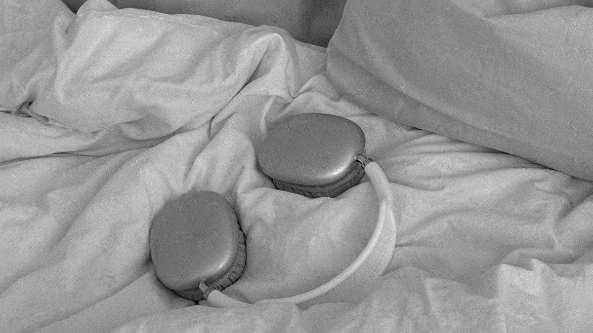 Stylish wireless headphones on a bed with pillows, in a monochrome theme. via Pexels