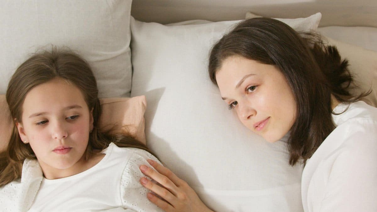 A serene moment between a mother and daughter, lying in bed, demonstrating love and warmth. via Pexels