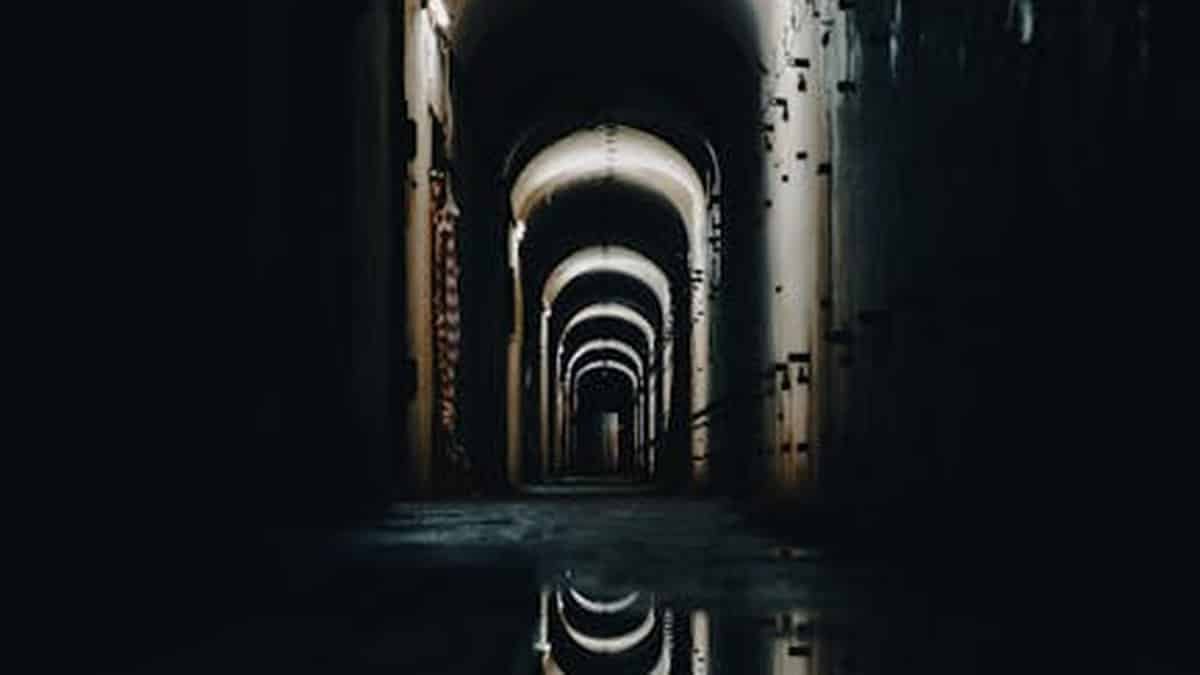 Eerie illuminated tunnel with water reflections creating a mysterious atmosphere. via Pexels