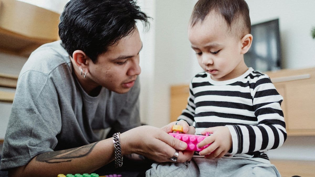 A father and son enjoy quality time together indoors, playing with colorful toys. via Pexels