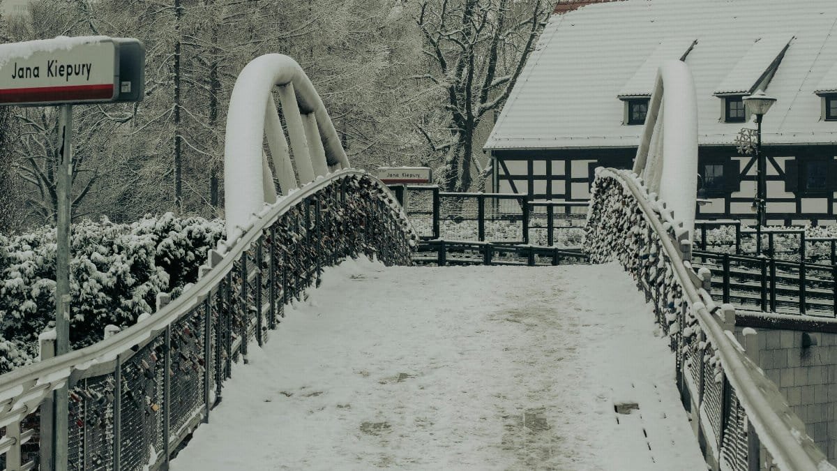 A serene winter scene showcasing a snow-covered bridge and trees in Bydgoszcz, Poland. via Pexels