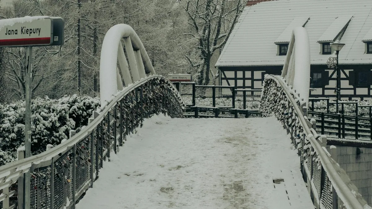 A serene winter scene showcasing a snow-covered bridge and trees in Bydgoszcz, Poland. via Pexels