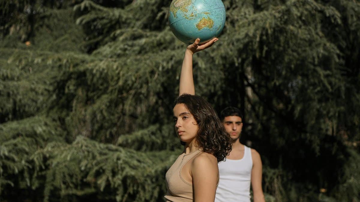 Young woman holds a globe aloft, symbolizing global unity and environmental awareness. via Pexels