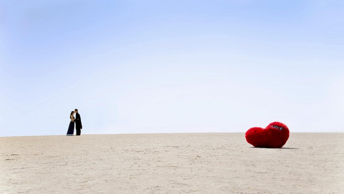 A couple embracing in the vast Sambhar desert with a plush heart in the foreground. via Pexels