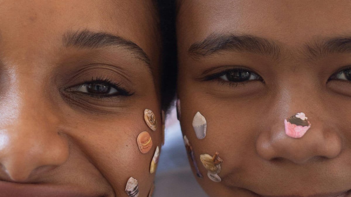 Close-up of a smiling mother and daughter wearing cute face stickers, expressing joy and bonding. via Pexels