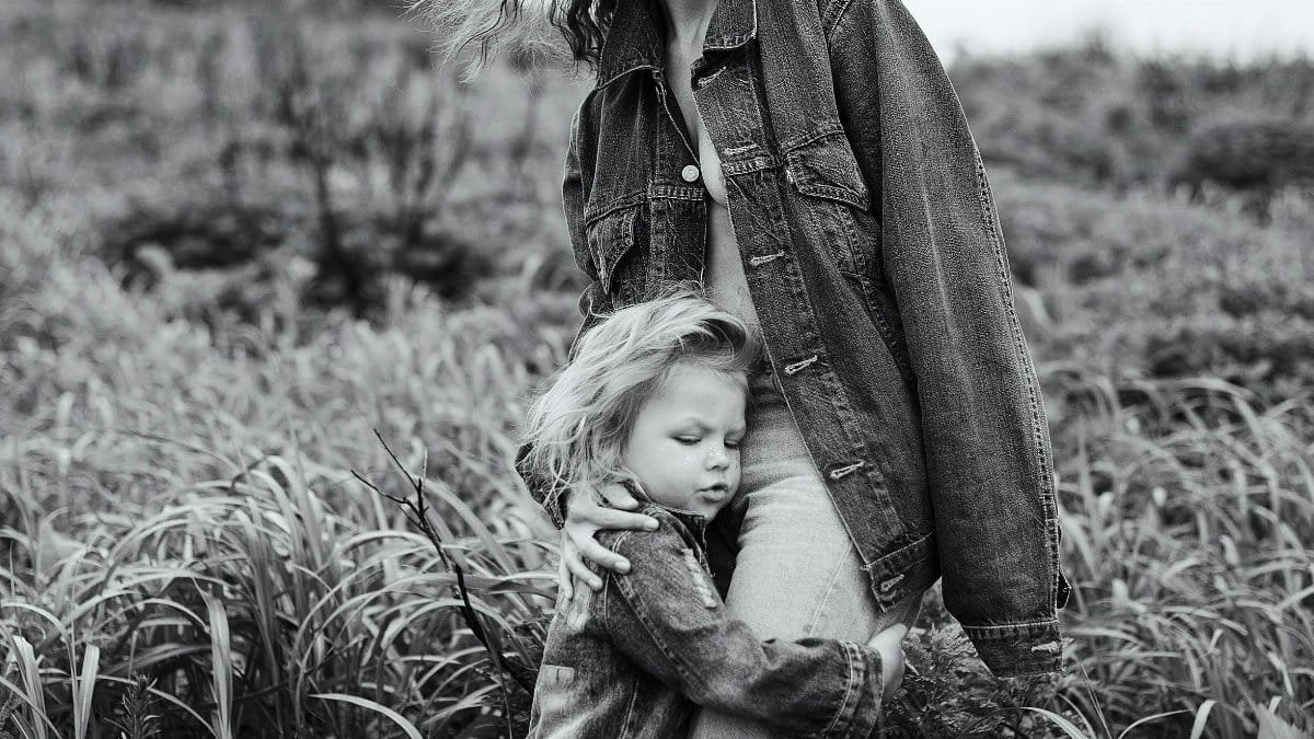 A touching black and white portrait of a mother and daughter embracing in a lush field. via Pexels