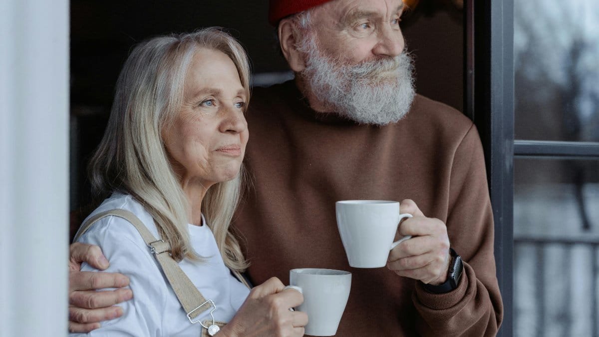 A senior couple embraces while enjoying coffee, symbolizing love and companionship. via Pexels