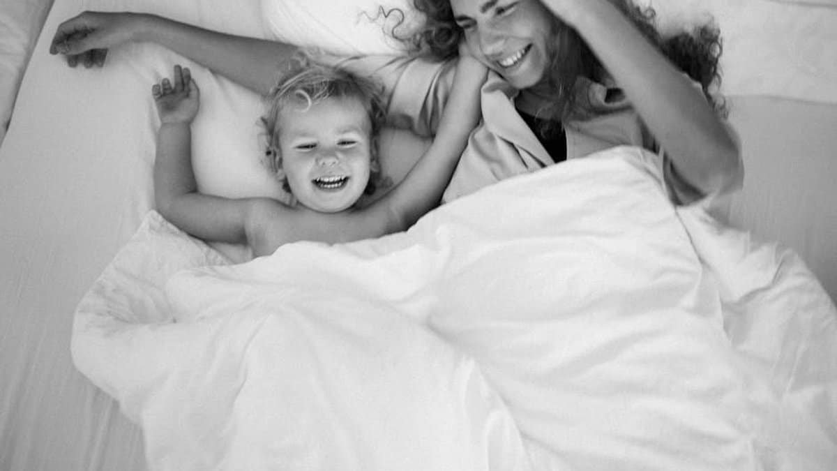 A heartwarming black and white portrait of a mother and child laughing in bed. via Pexels