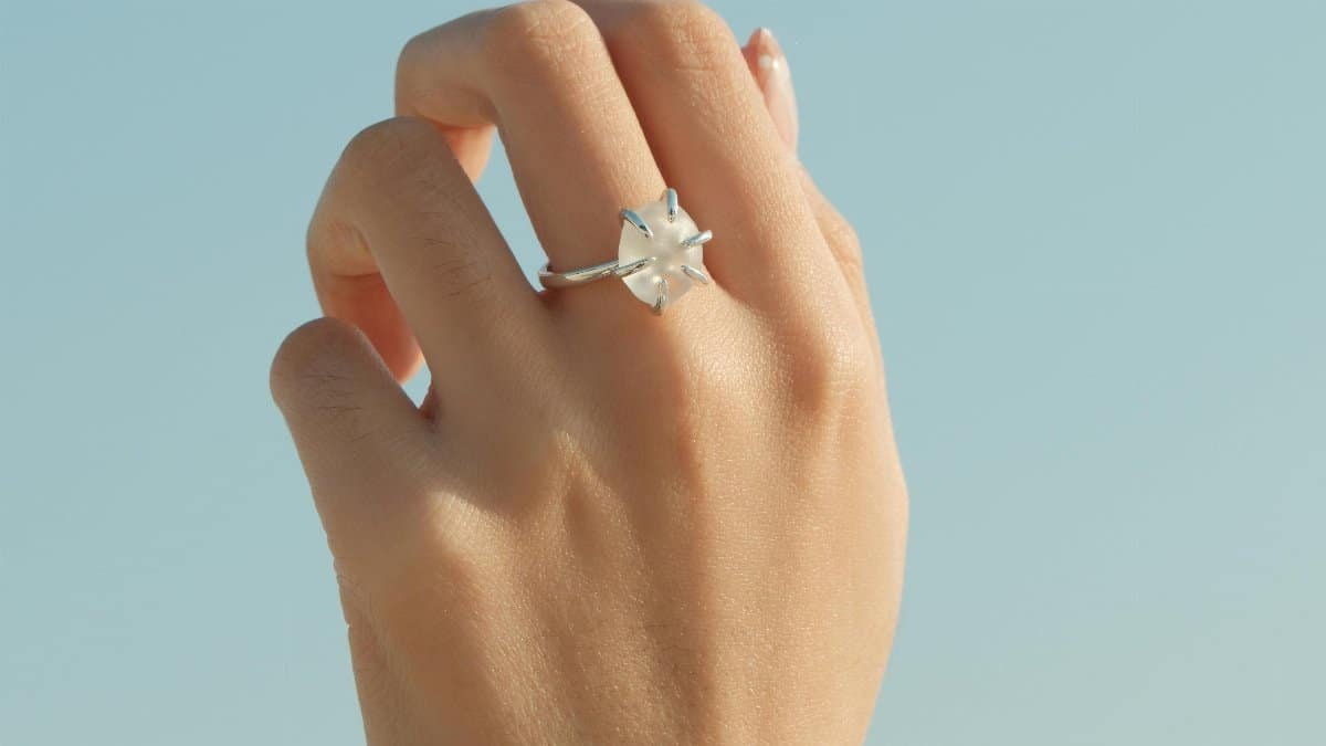 A close-up of a hand wearing a diamond ring against a clear blue sky, showcasing elegance and simplicity. via Pexels