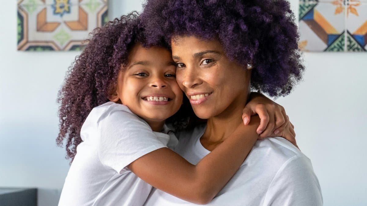 A joyful embrace between a smiling mother and daughter indoors, capturing love and togetherness. via Pexels