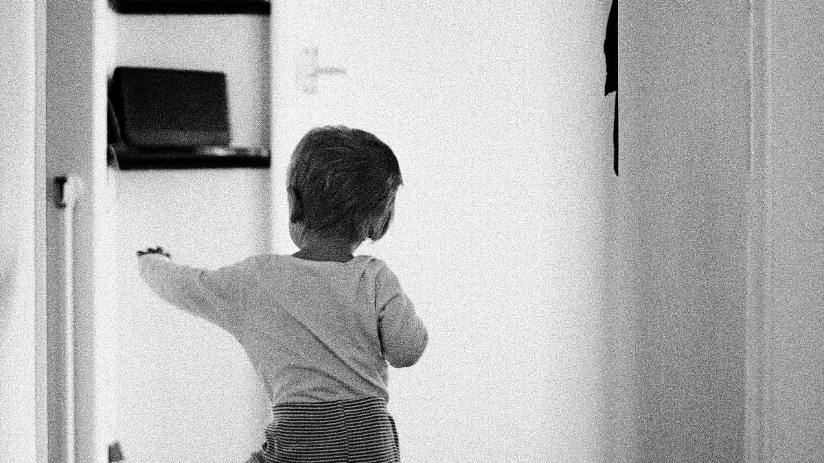 Black and white photo of a toddler taking steps in a hallway. via Pexels