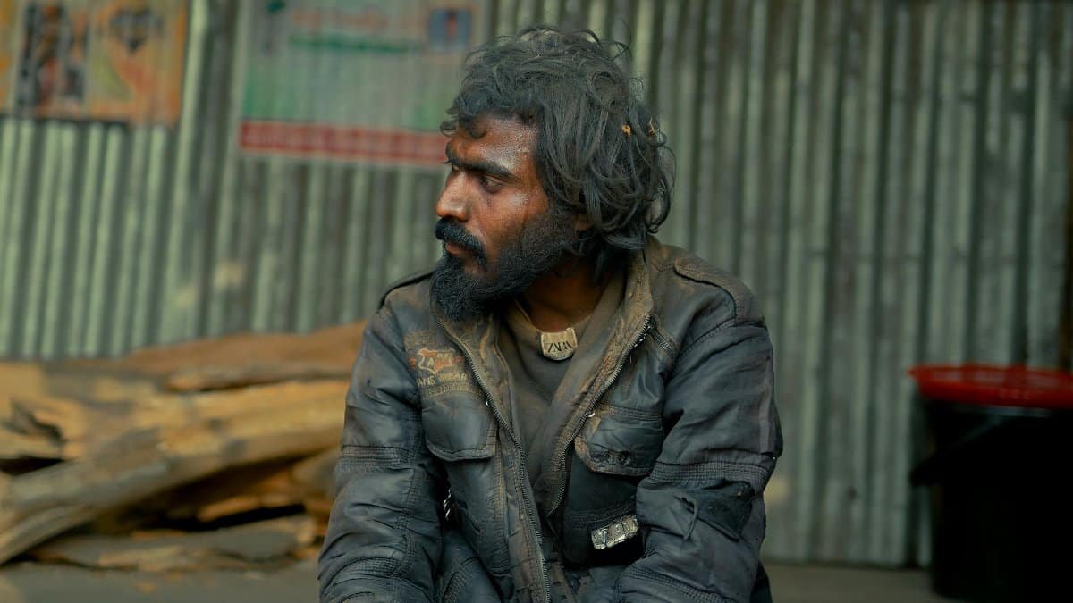 A contemplative man with long hair sits outdoors in Bangladesh, reflecting life. via Pexels