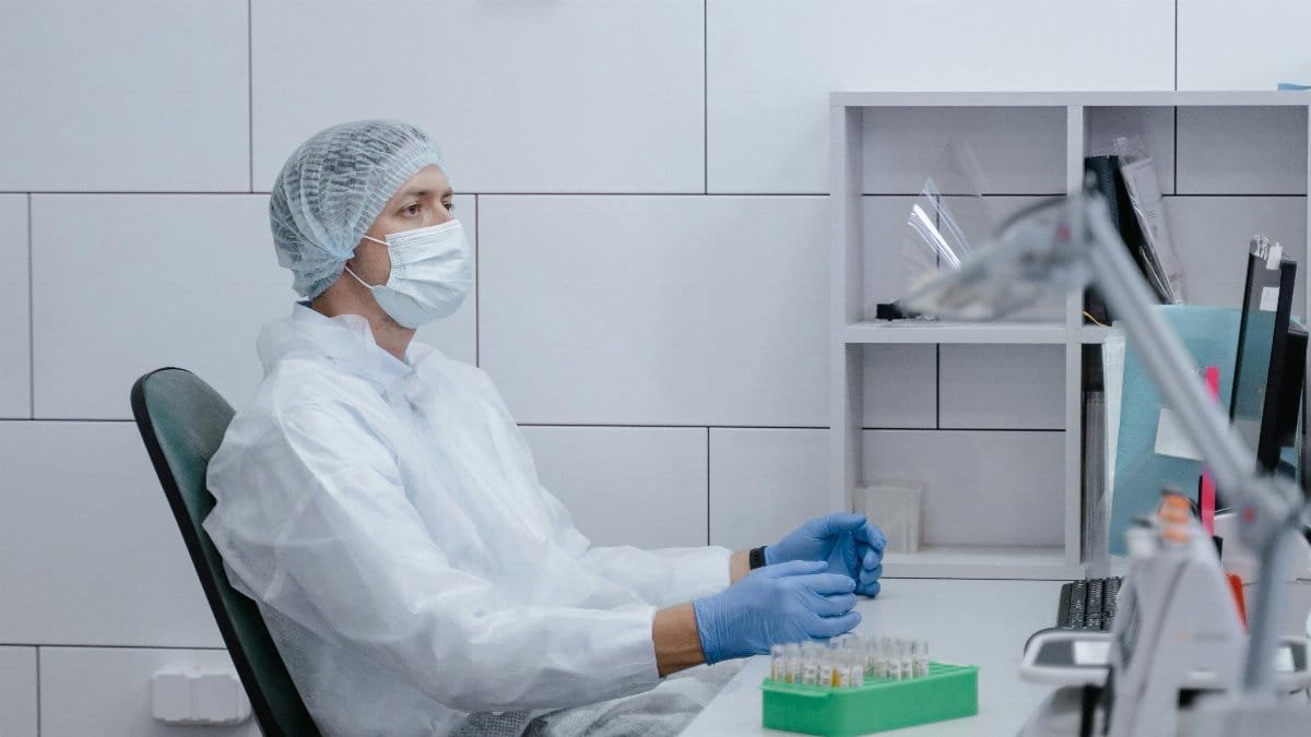 A medical technician in protective gear conducts laboratory analysis. via Pexels