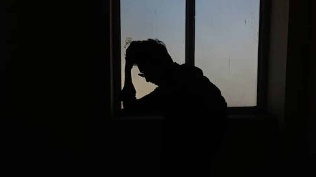 Silhouette of a person standing alone at a window, evoking an emotional mood. via Pexels