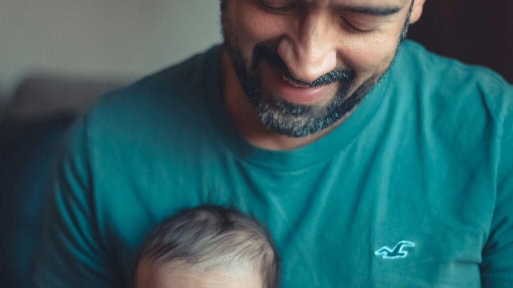 A touching indoor portrait of a beaming father holding his baby, expressing love and happiness. via Pexels