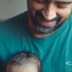 A touching indoor portrait of a beaming father holding his baby, expressing love and happiness. via Pexels