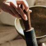 A person holds a Tibetan singing bowl with a mallet, symbolizing meditation and relaxation. via Pexels