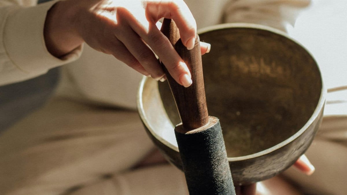 A person holds a Tibetan singing bowl with a mallet, symbolizing meditation and relaxation. via Pexels