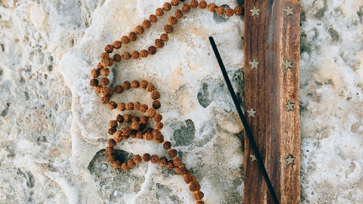 Top view of incense holder and mala beads on textured stone, promoting calm. via Pexels