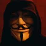 A person wearing a Guy Fawkes mask and hood in a dark, mysterious setting. via Pexels