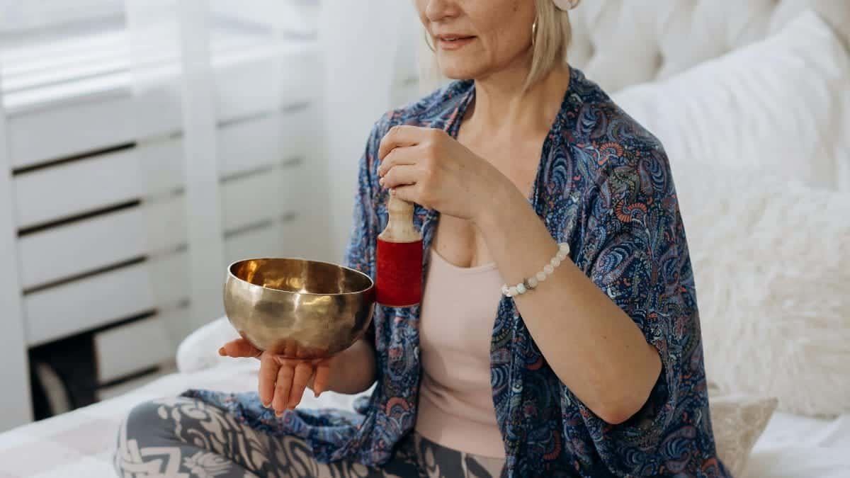 Elderly woman in a peaceful setting meditating with a singing bowl, embracing tranquility and mindfulness. via Pexels