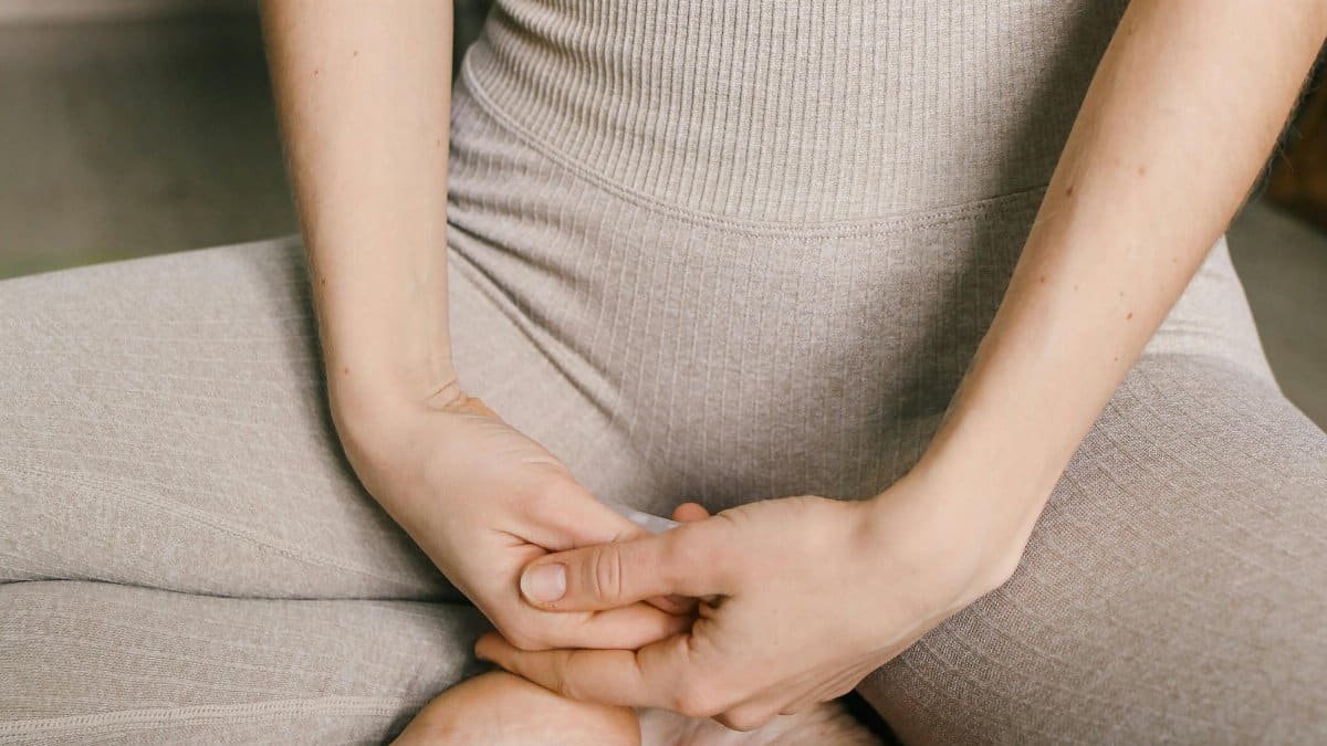 Close-up of a woman in a meditative pose wearing comfortable activewear indoors. via Pexels