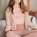 A serene adult woman meditates on a city rooftop, embodying relaxation and mindfulness amid urban surroundings. via Pexels