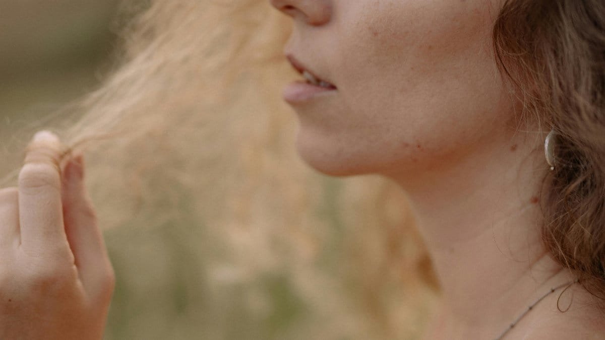 Close-up of a woman with curly hair in a natural outdoor setting, capturing a serene moment. via Pexels