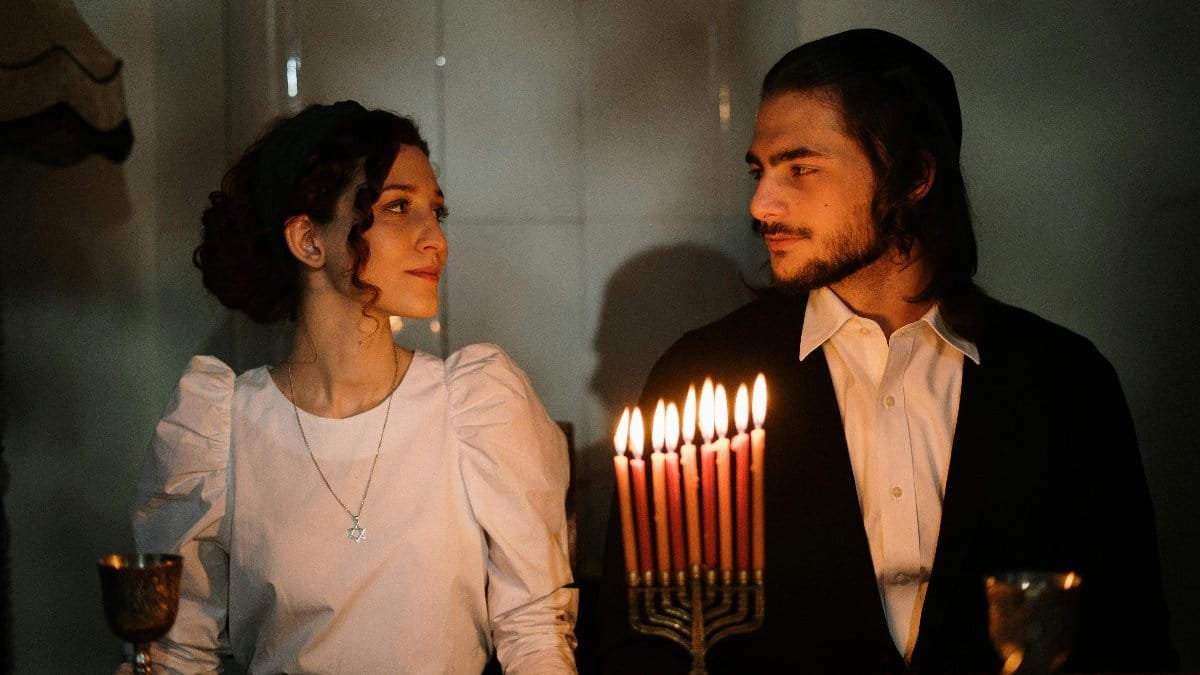 A couple enjoys a candlelit dinner celebrating Hanukkah with a menorah. via Pexels