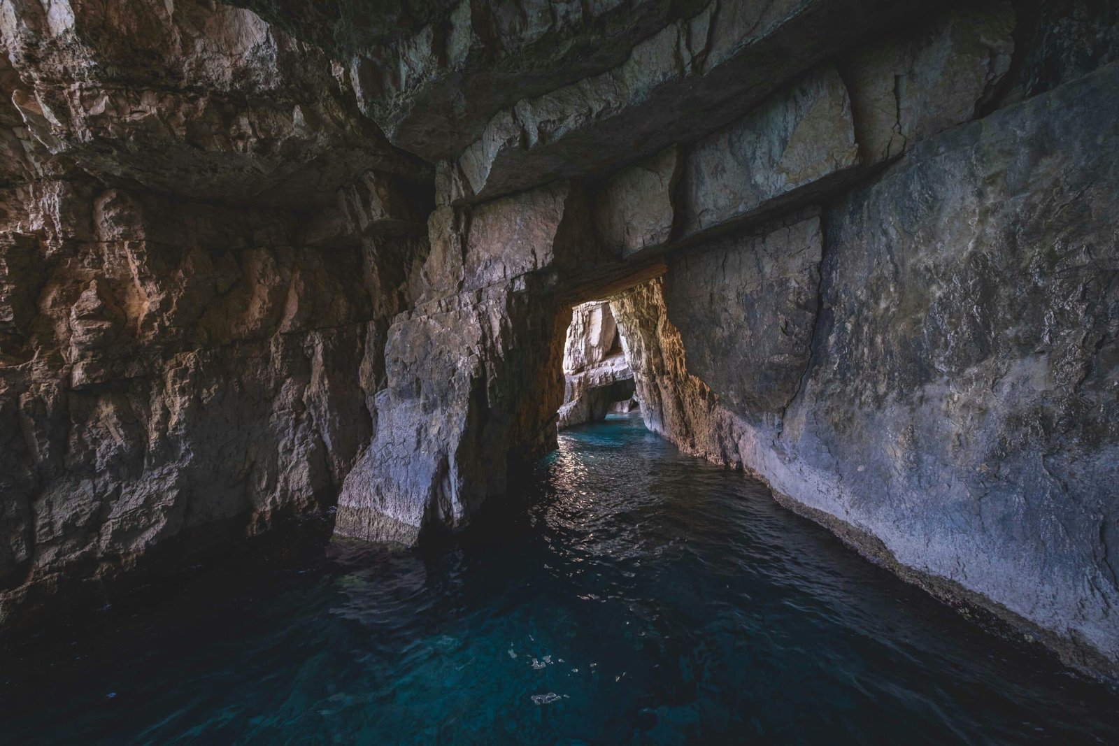 A cave with blue water and rocks