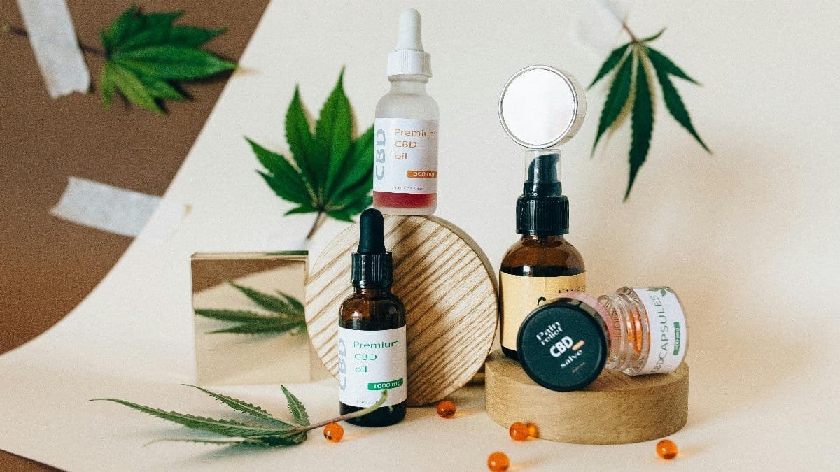 A collection of CBD oil products showcased with cannabis leaves on a neutral background. via Pexels