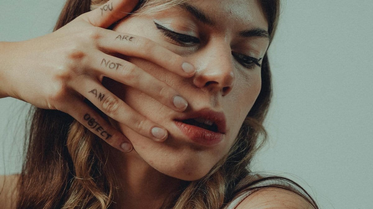 A close-up portrait of a woman with hand tattoos saying 'You Are Not An Object'. via Pexels