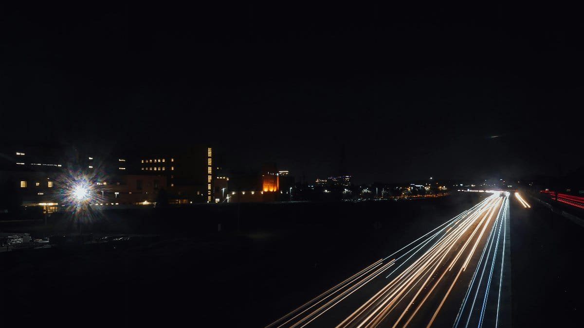 Nighttime cityscape featuring dynamic light trails across a bustling urban road. via Pexels