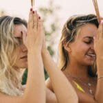 Two women meditating with incense outdoors, embracing summer tranquility. via Pexels