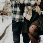 A loving couple embraces on a snow-covered path in Munich, capturing a warm moment of affection in winter. via Pexels