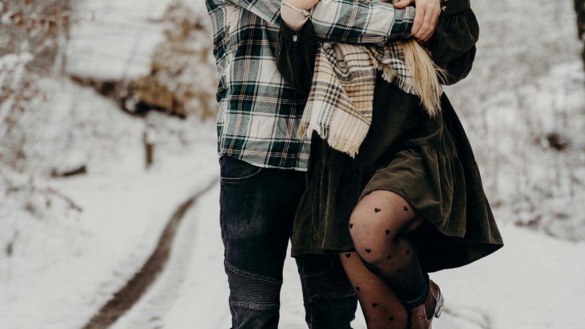 A loving couple embraces on a snow-covered path in Munich, capturing a warm moment of affection in winter. via Pexels