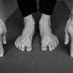 Monochrome image showing a yoga pose with focus on hands and feet stretching on a mat. via Pexels