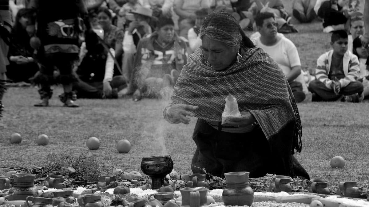 An indigenous woman performs a ritual with an audience watching closely in Mexico. via Pexels