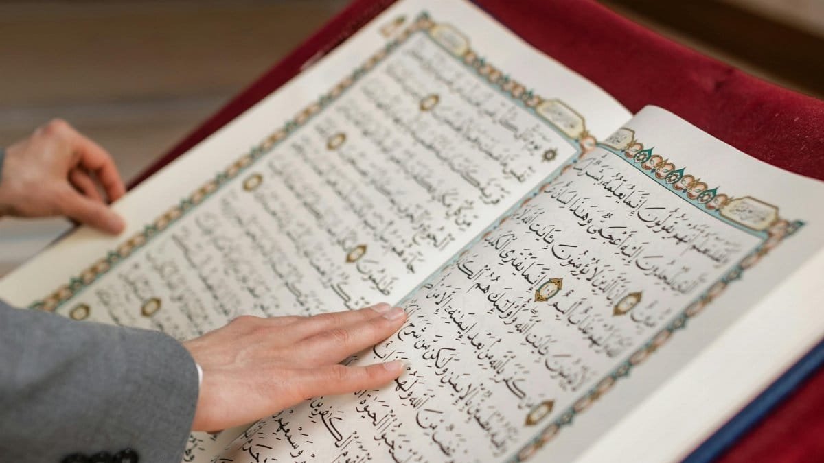 Close-up of a person engaging with an open Quran during Ramadan inside a mosque. via Pexels