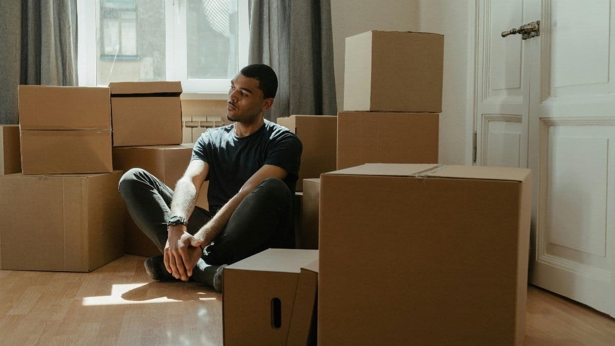 A man sitting in meditation pose among moving boxes, embracing tranquility during relocation. via Pexels