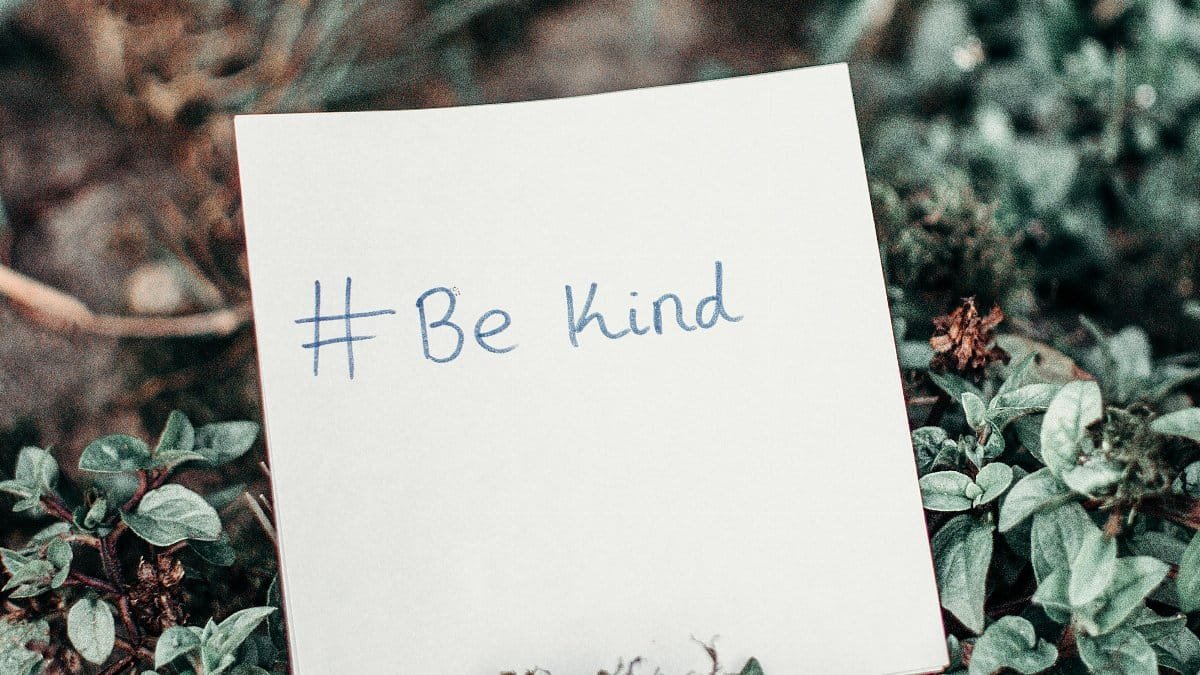 Close-up of an inspirational note with 'Be Kind' hashtag placed on lush green grass. via Pexels