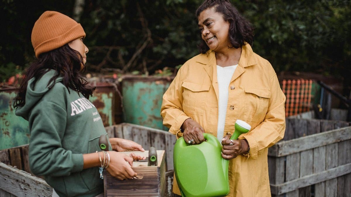 A woman and her daughter engage in outdoor gardening, sharing a moment with tools in hand. via Pexels