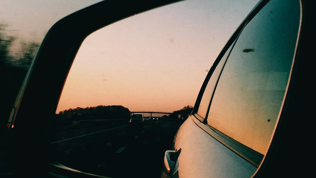 Bright sundown sky over asphalt highway and trees through mirror of modern automobile via Pexels