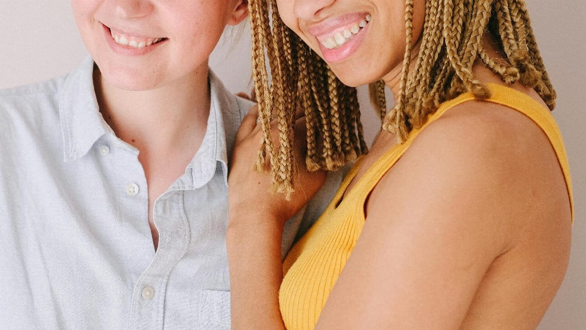 Two friends sharing a joyful embrace indoors, showcasing affection and friendship. via Pexels