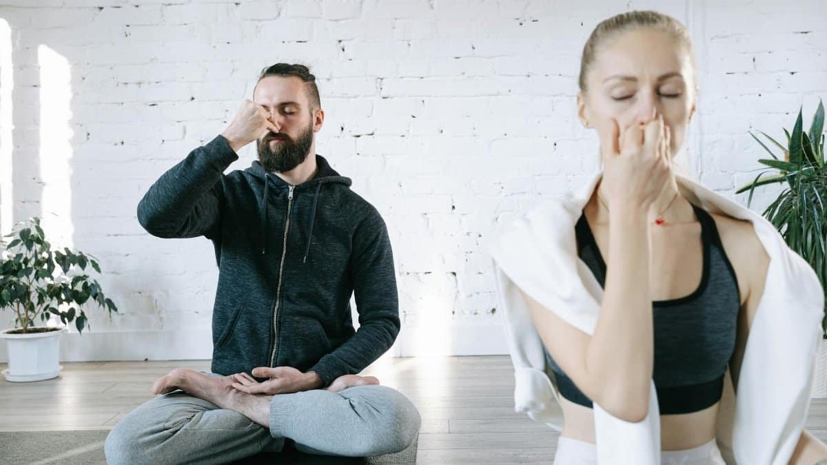 A serene couple practicing pranayama breathing techniques in a bright indoor space, fostering mindfulness and relaxation.