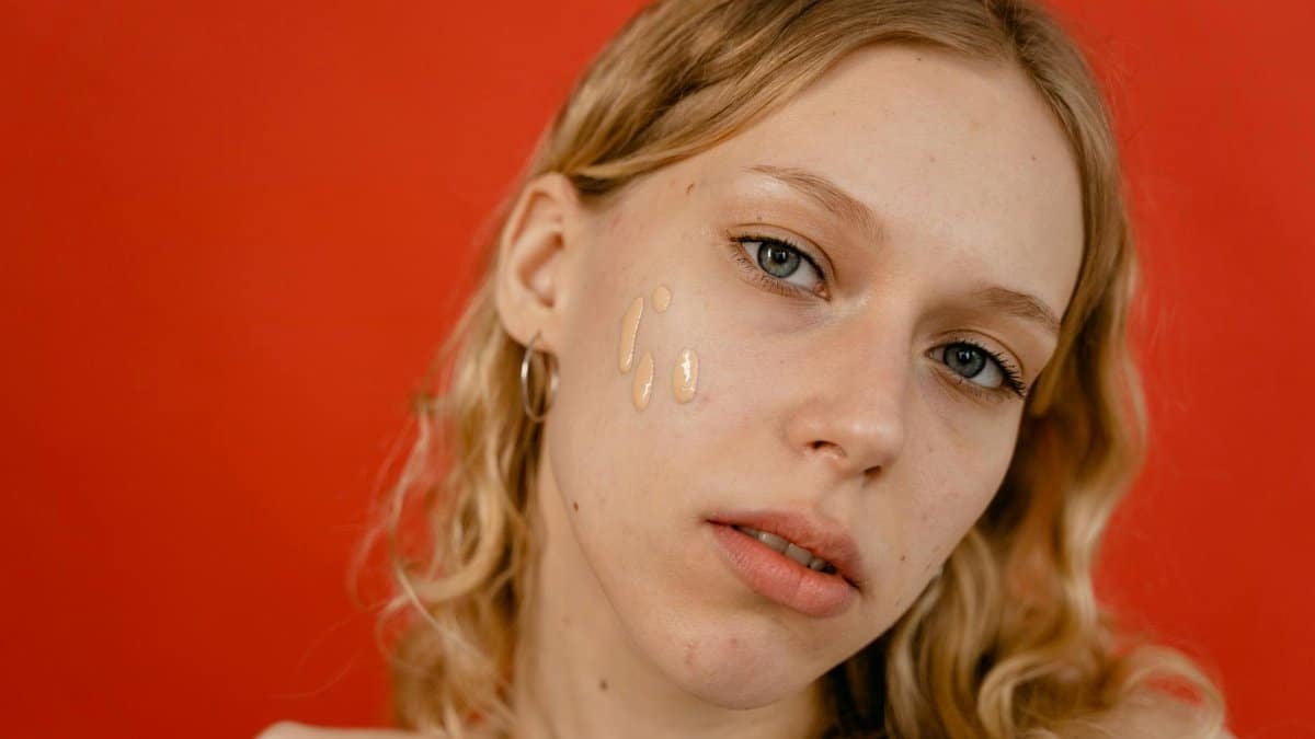 A close-up portrait of a woman applying foundation, showcasing natural beauty and skincare.